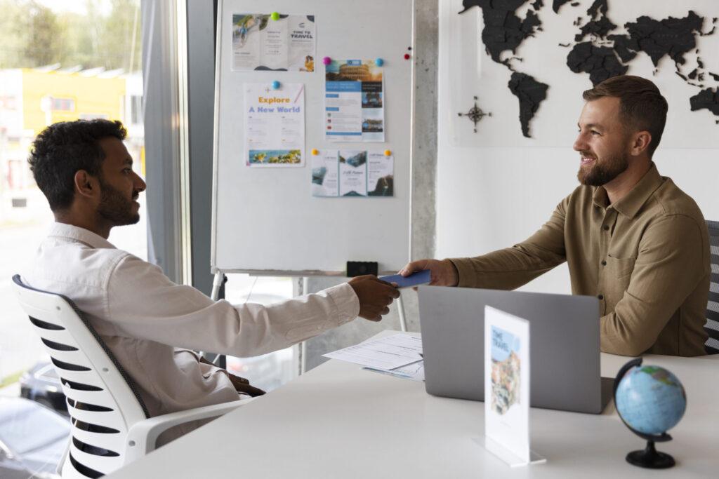 Two men shaking hands at a desk in an office, symbolizing a successful business agreement or partnership.